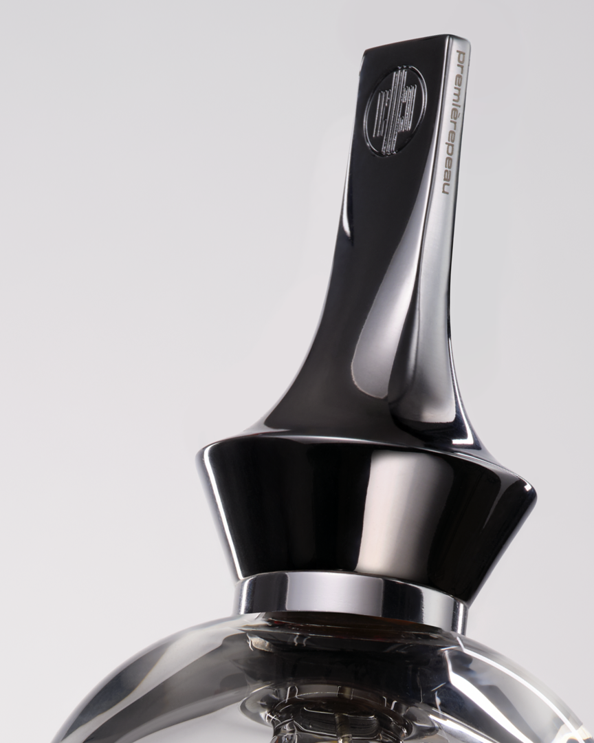 Close-up of a metallic bottle cap with a brand logo on a light gray background